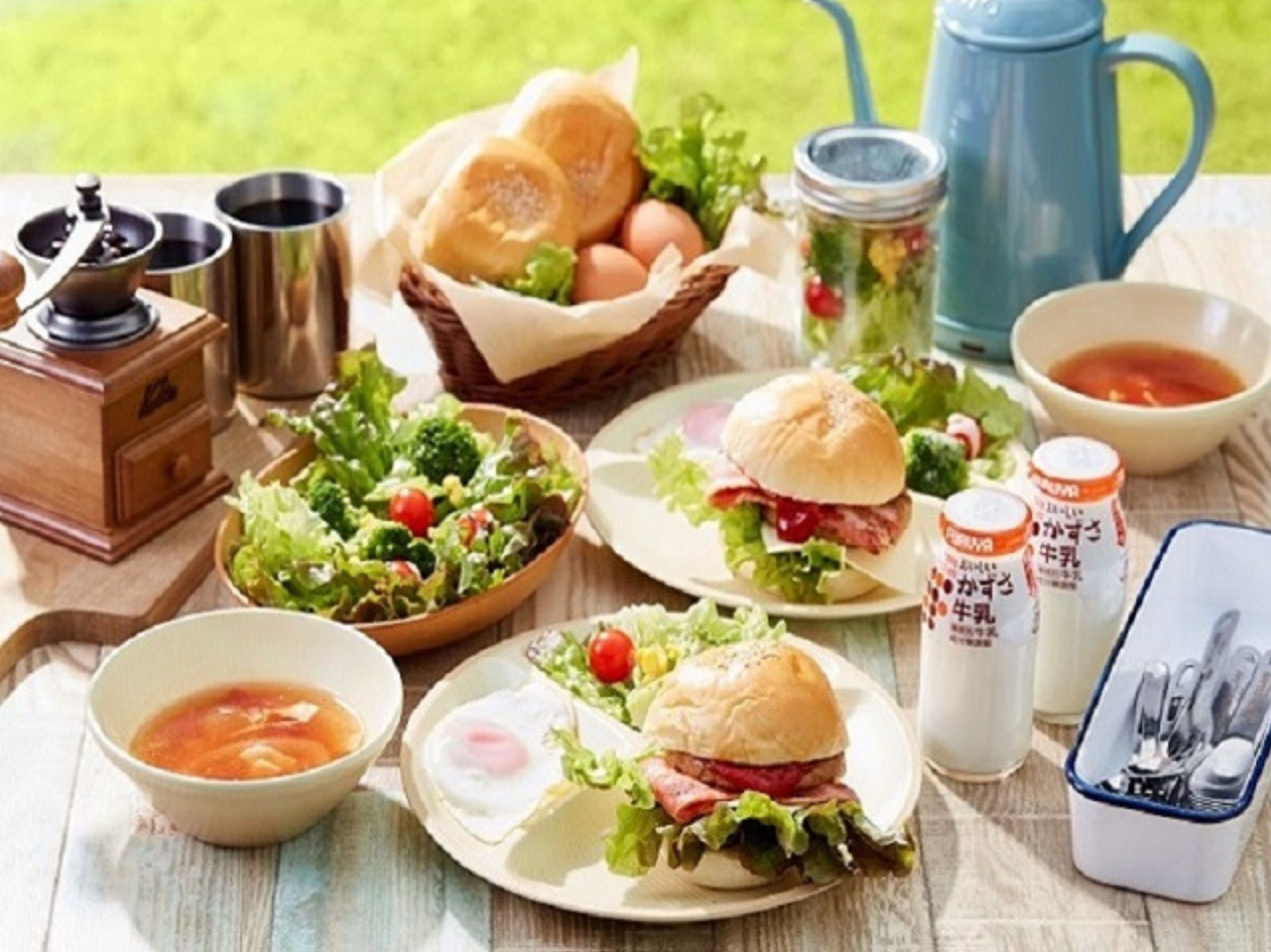 A picnic setup with food items including sandwiches, salad, eggs, and condiments.