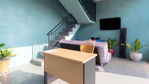 Ein Zimmer mit Schreibtisch, Stuhl und einer Treppe.