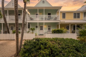 A two-story building with a porch, a picket fence, and a well-maintained garden.