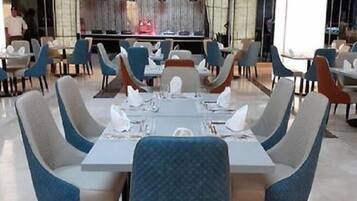 A modern dining area with a central table set for four, surrounded by blue upholstered chairs.