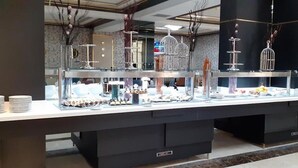 A buffet setup with multiple glass display cases containing various food items. - RODINA (Oran)