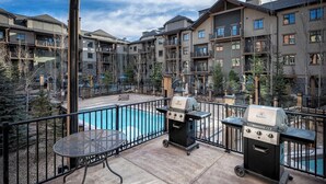 Une terrasse sur le toit avec une piscine, des barbecues et une vue sur des immeubles à plusieurs étages.