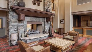 Un salon chaleureux avec une cheminée en pierre, des fauteuils en cuir et un tapis à motifs écossais.