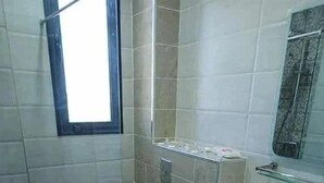 A small bathroom with a toilet, a sink, and a mirror. - Medina Park Hotel (Algiers)