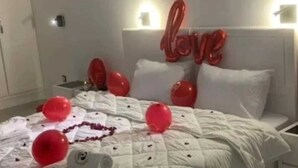 A bed with a white quilt, red balloons, and a 'love' sign on the headboard. - Medina Park Hotel (Algiers)
