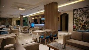 A spacious hotel lobby with multiple seating areas, including sofas and tables. There is a reception desk in the background, and the space is well-lit with ceiling lights. - Lynatel Palace (Ouargla)