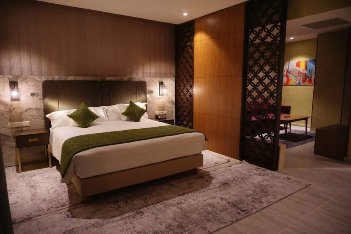 A modern bedroom with a large bed, two bedside tables, and a decorative wall panel.