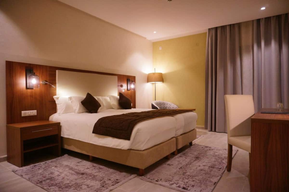 A hotel room with a double bed, bedside tables, a lamp, a chair, and a small table.