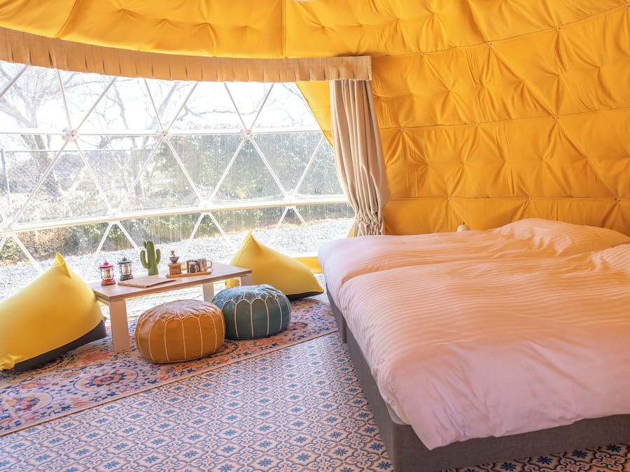 A cozy room with a bed, pillows, a table, and a window overlooking a snowy landscape.