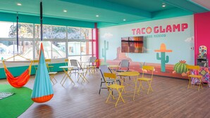 A vibrant room with a mural of cacti and a sign reading "TACO GLAMP THE MEXICO".
