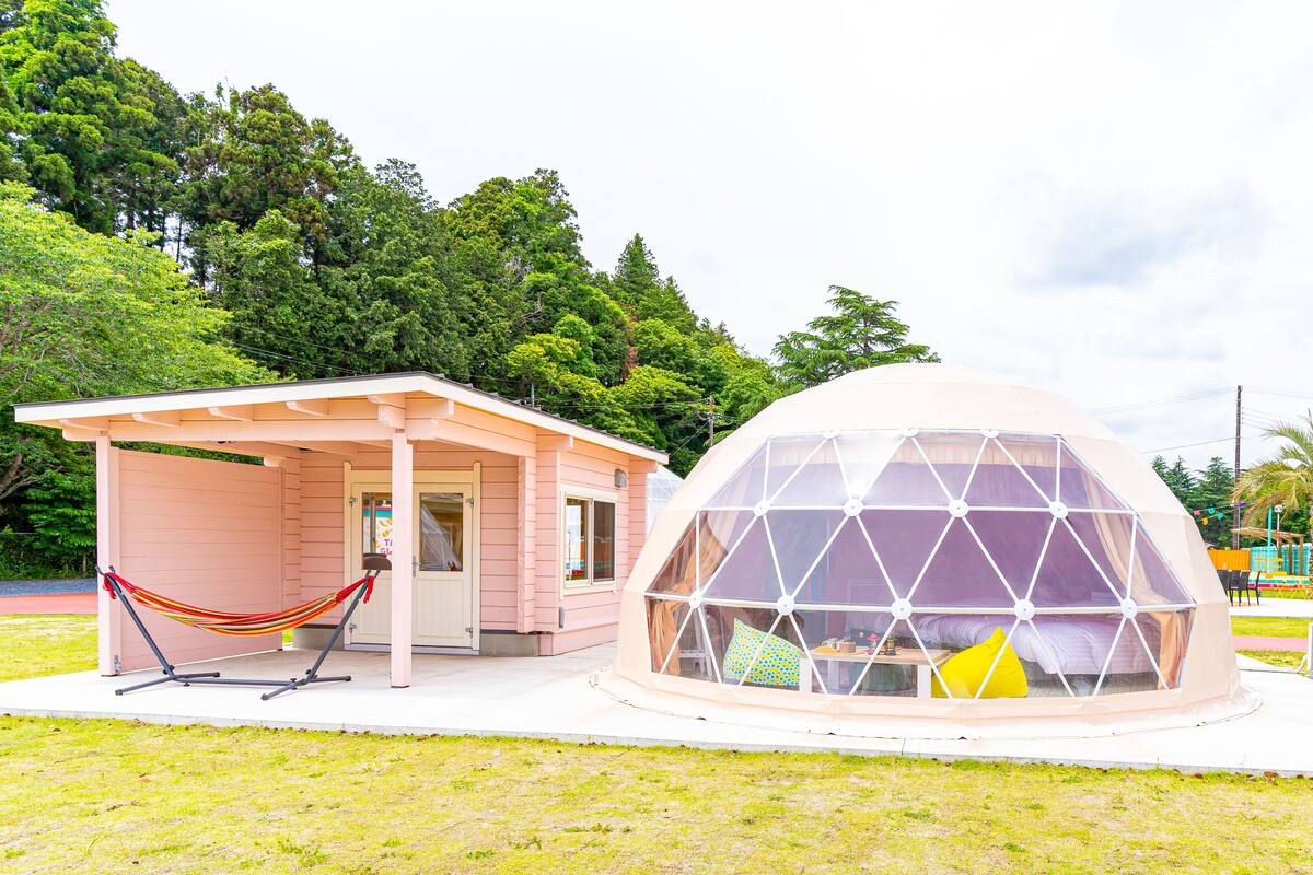Un edificio rosa con una hamaca y una estructura geodésica en forma de cúpula.