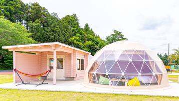 A pink building with a hammock and a geodesic dome structure.