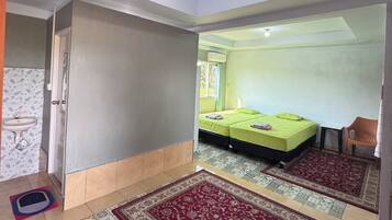 A room with a bed, a small table, a chair, a window, and a ceiling light.
