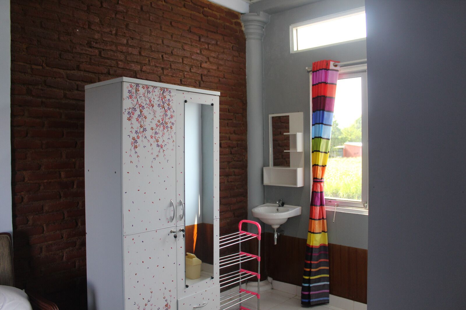 A bathroom with a white cabinet, a sink, and a colorful striped shower curtain.