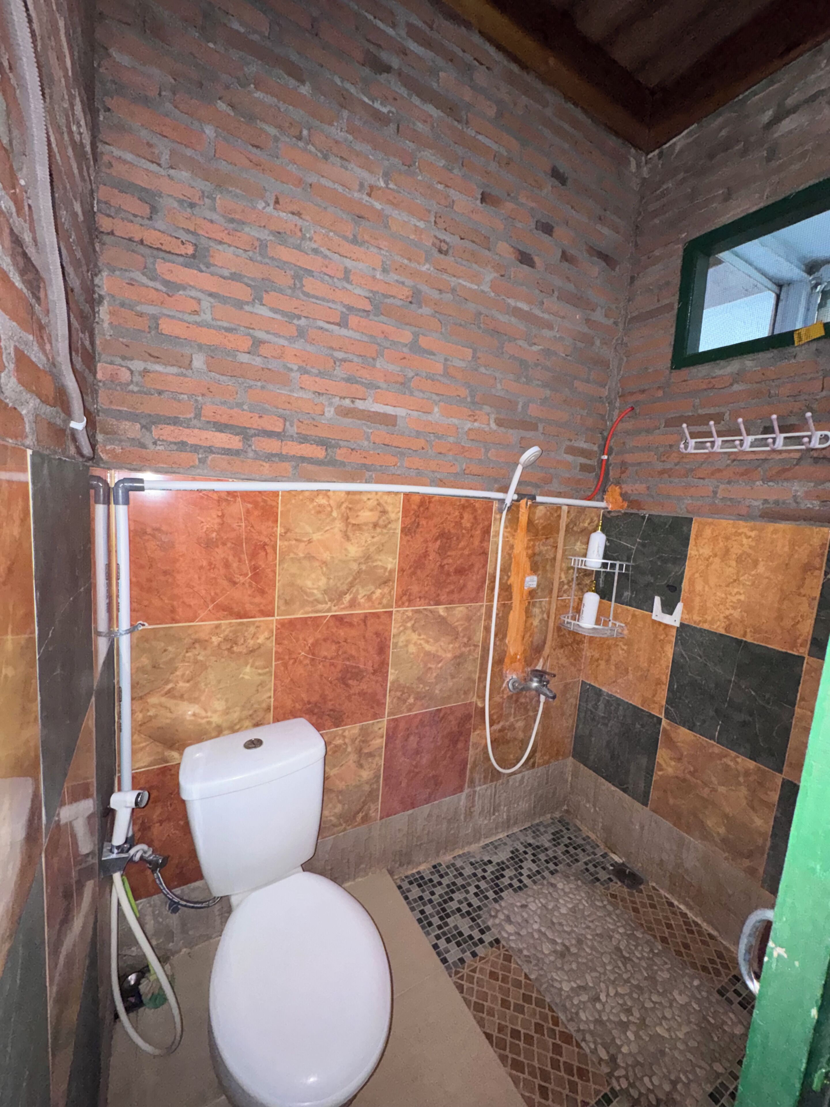 Ein Badezimmer mit Toilette, Dusche und gefliesten Wänden.