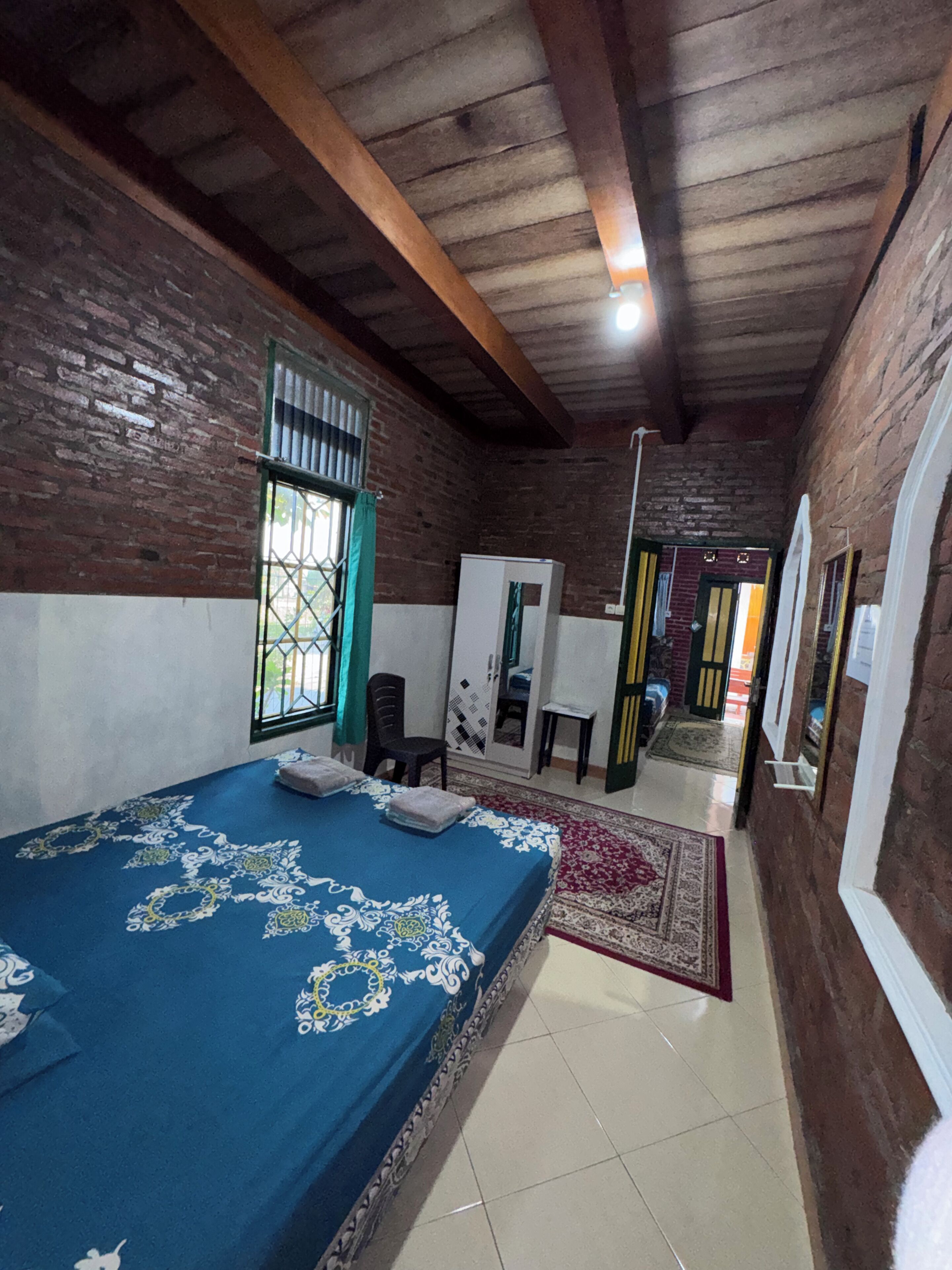 Una habitación con cama, una silla, un escritorio y un armario.