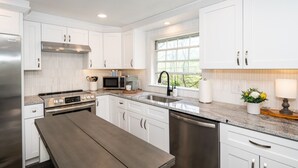 A modern kitchen with white cabinets, stainless steel appliances, a granite countertop, and a window providing natural light. - Watershed,  A River Retreat (Loveland)