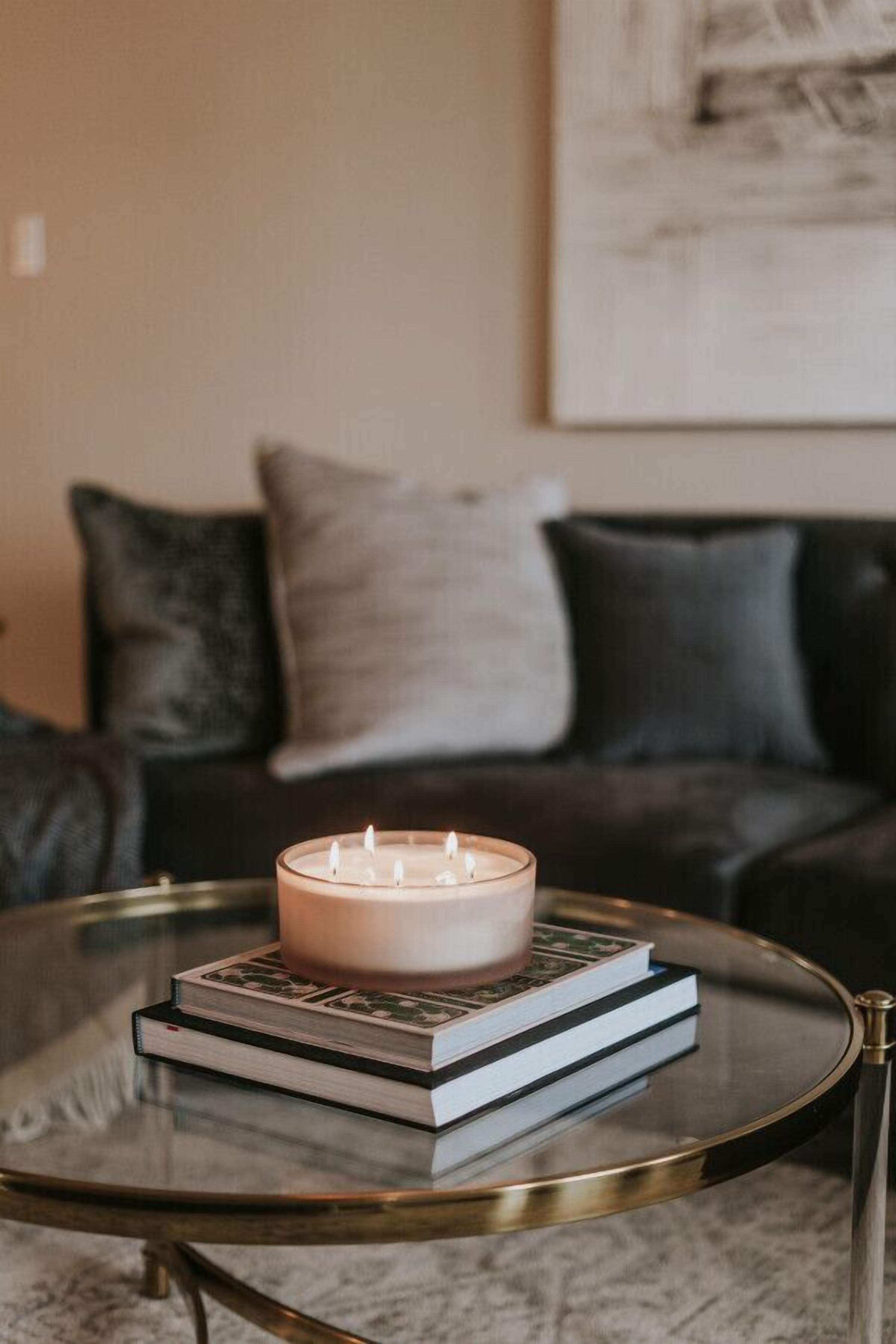 Une table basse en verre avec une bougie et des livres.