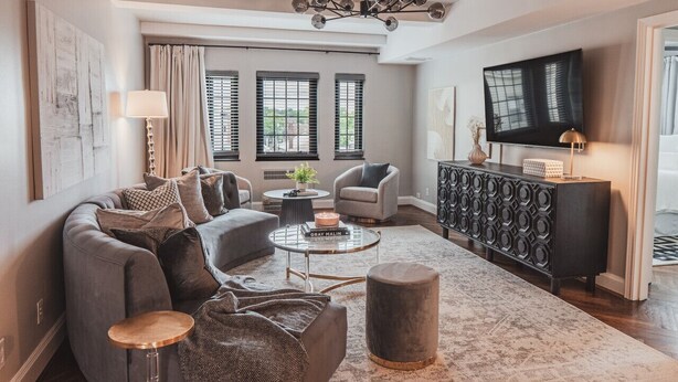 Ein modernes Wohnzimmer mit einem grauen Sofa, einem runden Couchtisch und einer schwarzen Ablagetisch.