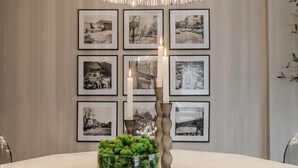 Ein Essbereich mit einem runden Tisch, einer dekorativen Pendelleuchte und schwarzen, weißen Fotos in Rahmen an der Wand.