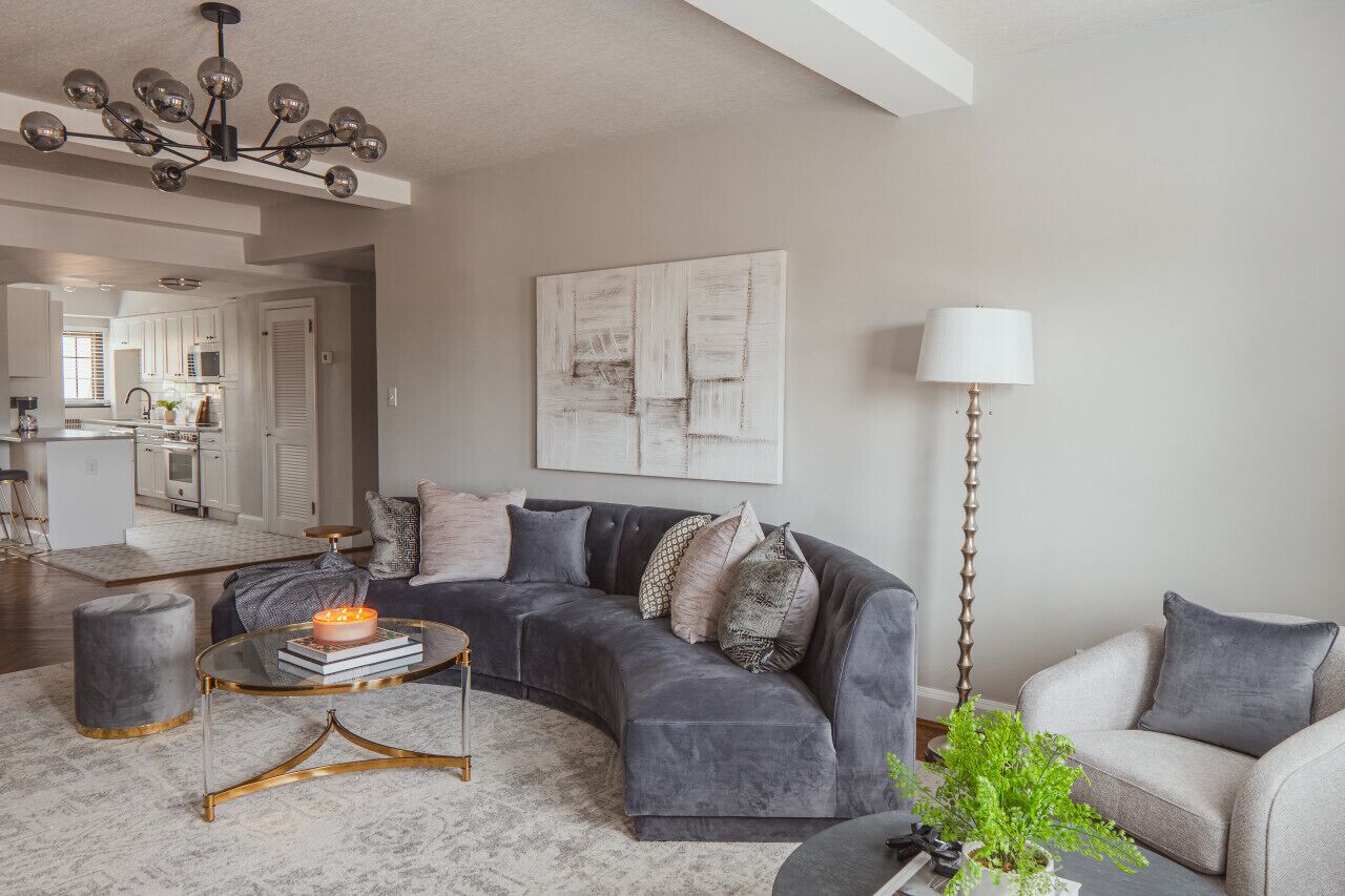 A modern living room with a grey sectional sofa, a round coffee table, and a floor lamp.