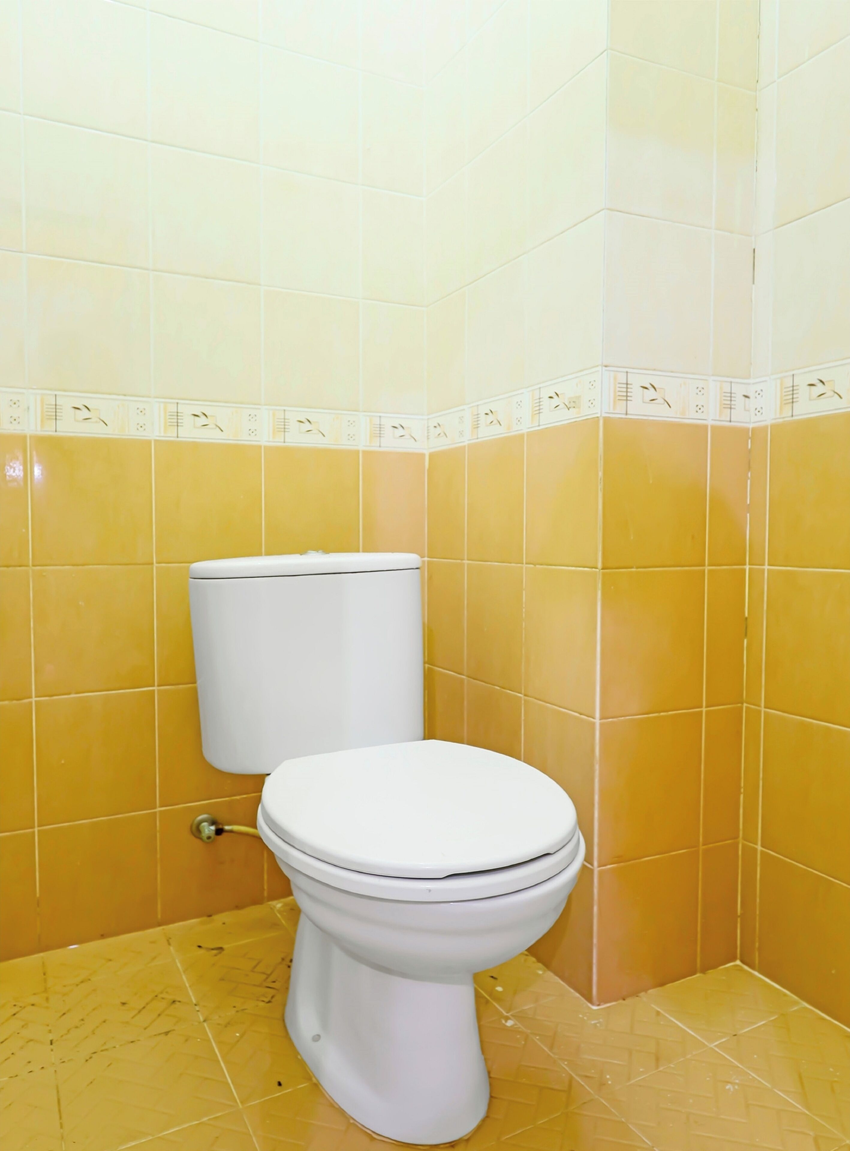 Une salle de bain avec des carreaux jaunes et des toilettes blanches.