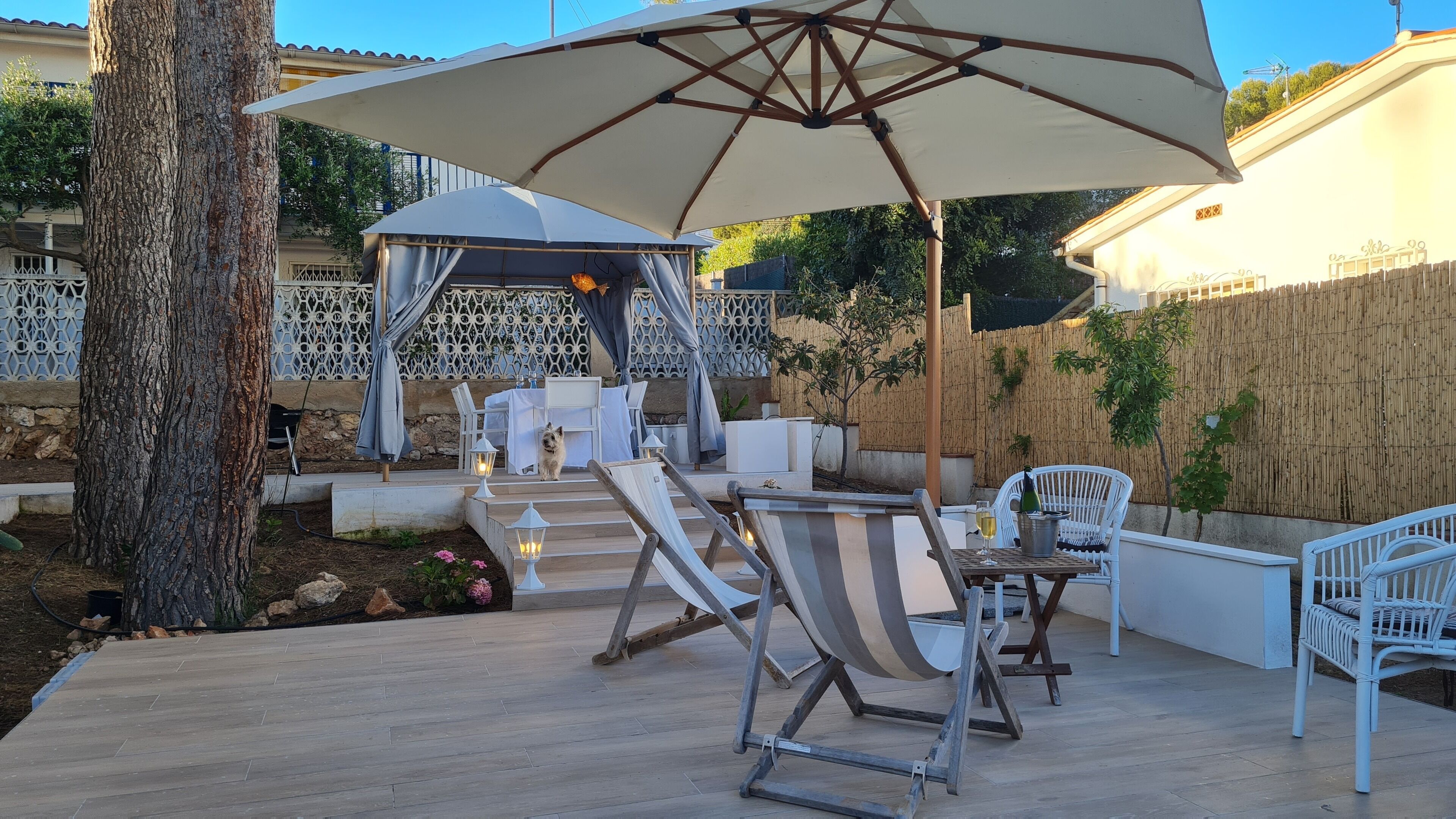 En udendørs patio med pergola, lounge stole og et spiseområde.