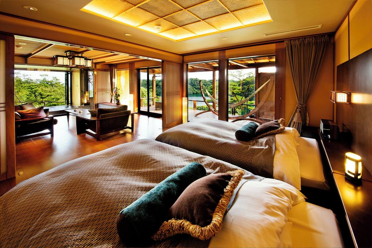 A hotel room with two beds, a desk, and a view of the outdoors.
