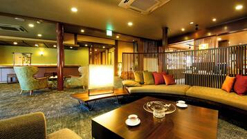 A modern hotel lobby with a wooden reception desk, seating area, and a coffee table with a cup and saucer.