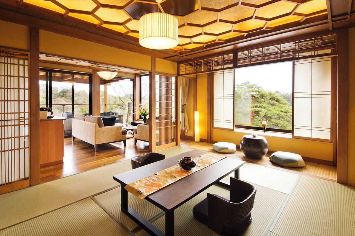 A traditional Japanese room with tatami flooring, a low table with a tea set, and sliding doors.