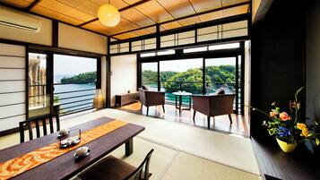 Experience serene views of lush green landscapes from this spacious room, featuring a dining area, seating space, and traditional Japanese touches.
