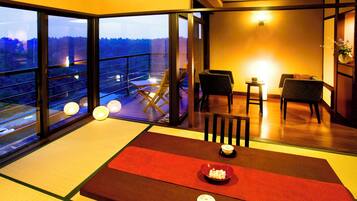 A traditional Japanese room with tatami flooring, a low table with a red runner, and a view of a balcony with a railing.