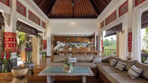 A spacious living area with a wooden ceiling, a sofa set, and a dining area in the background. - Villa Lembah Damai (Taro)