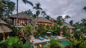 A resort with a pool, lounge chairs, and tropical vegetation. - Villa Lembah Damai (Taro)