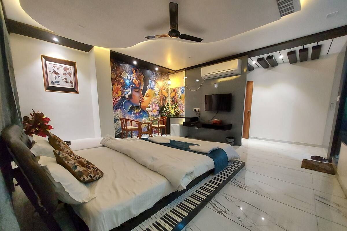 Ein modernes Schlafzimmer mit Bett, Klavier, Wandgemälde, Fernseher und Deckenventilator.