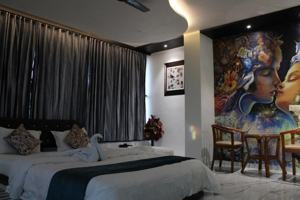 Un dormitorio con una cama grande, un mural en la pared y una zona de estar con sillas.