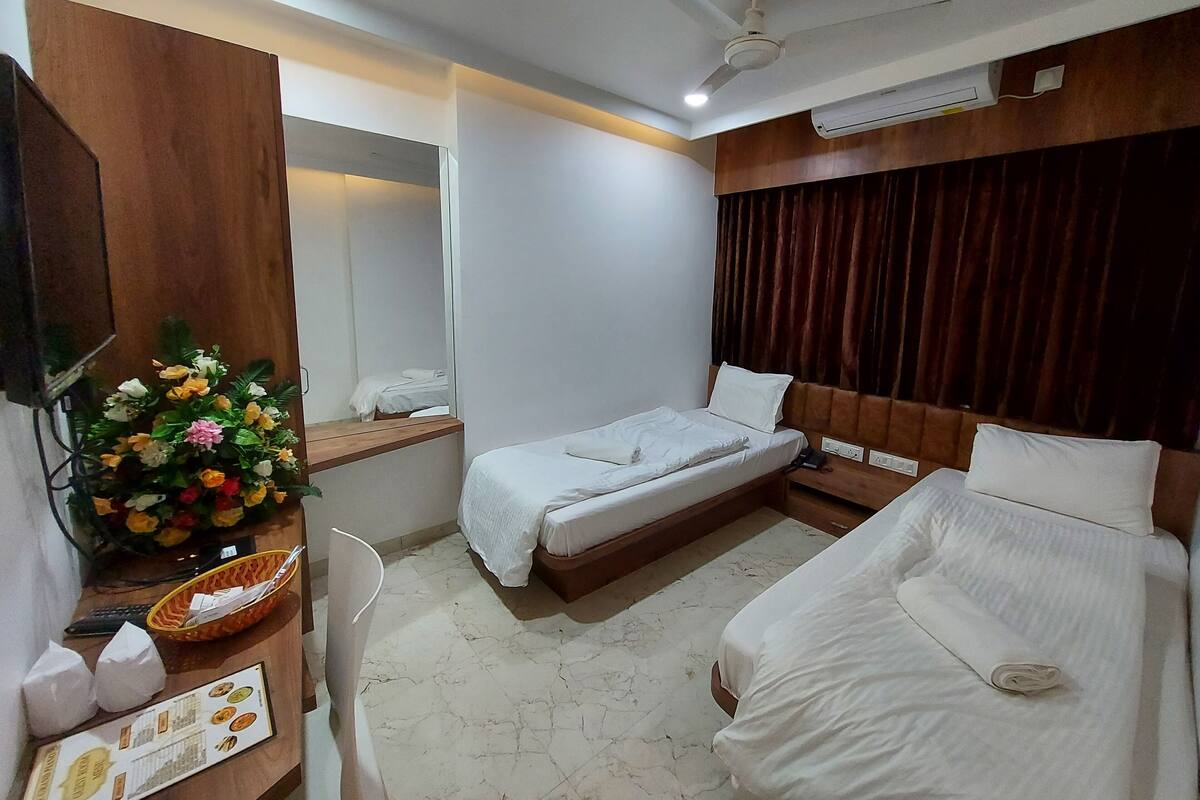 Ein Hotelzimmer mit Bett, Schreibtisch, Computer, Fernseher und einer Zimmerpflanze.