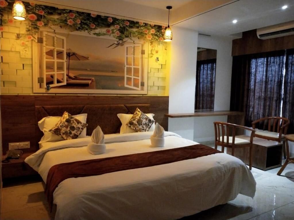 A hotel room with a large bed, a wooden headboard, a small desk, and a chair.