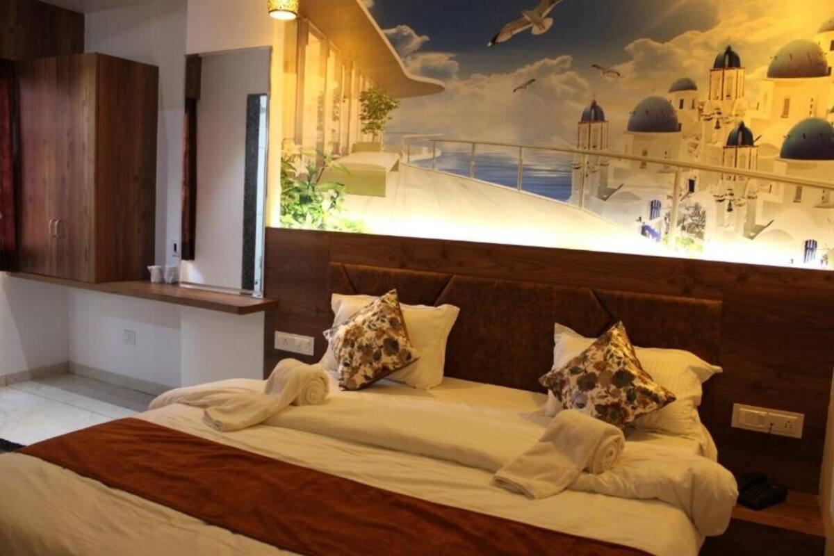 Ein Hotelzimmer mit einem großen Bett, einem hölzernen Kopfteil und einem Wandbild mit einer Küstenansicht.