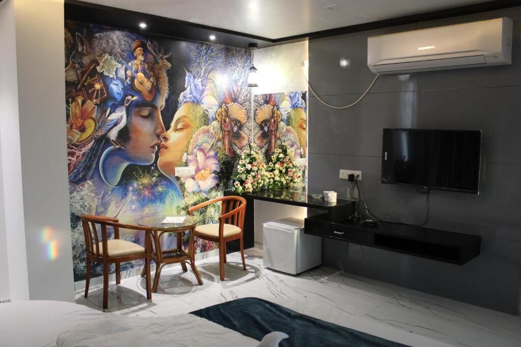 A modern room with a mural, a dining area, a TV, and a small kitchenette.