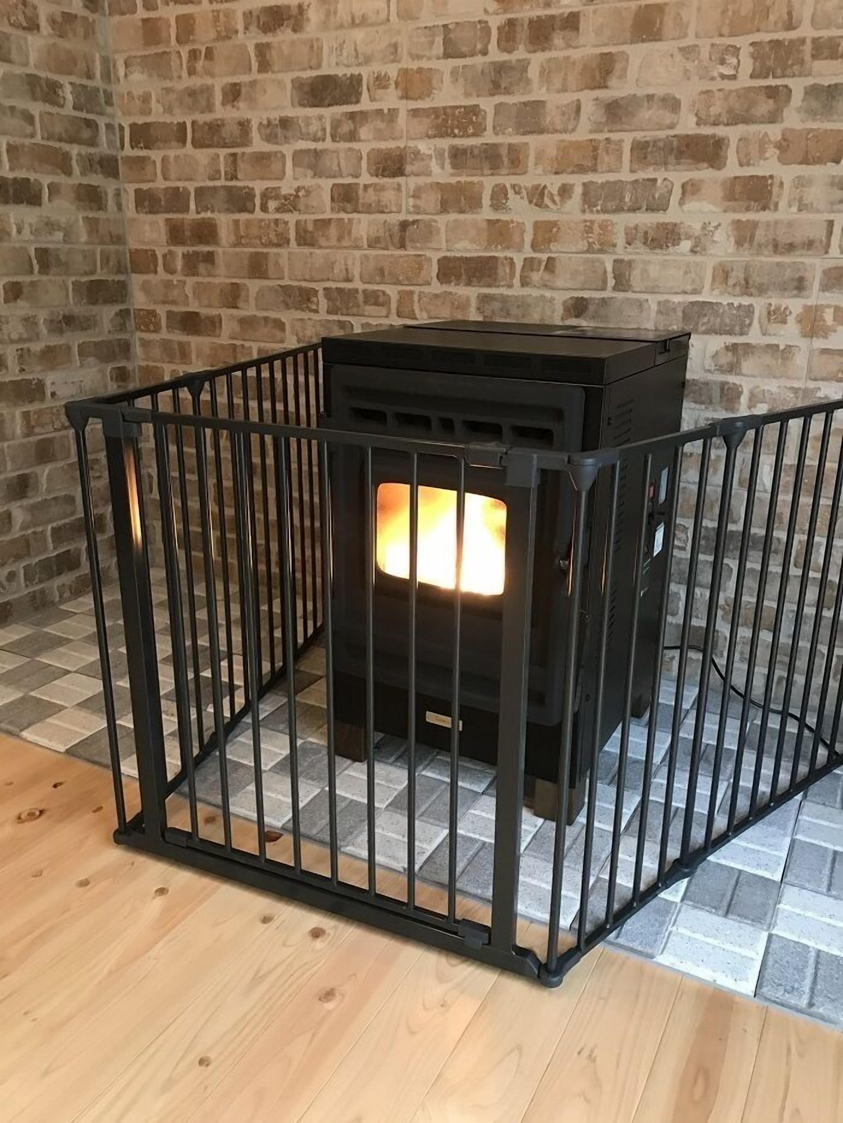 A wood-burning stove with a metal fence in front, set against a brick wall.