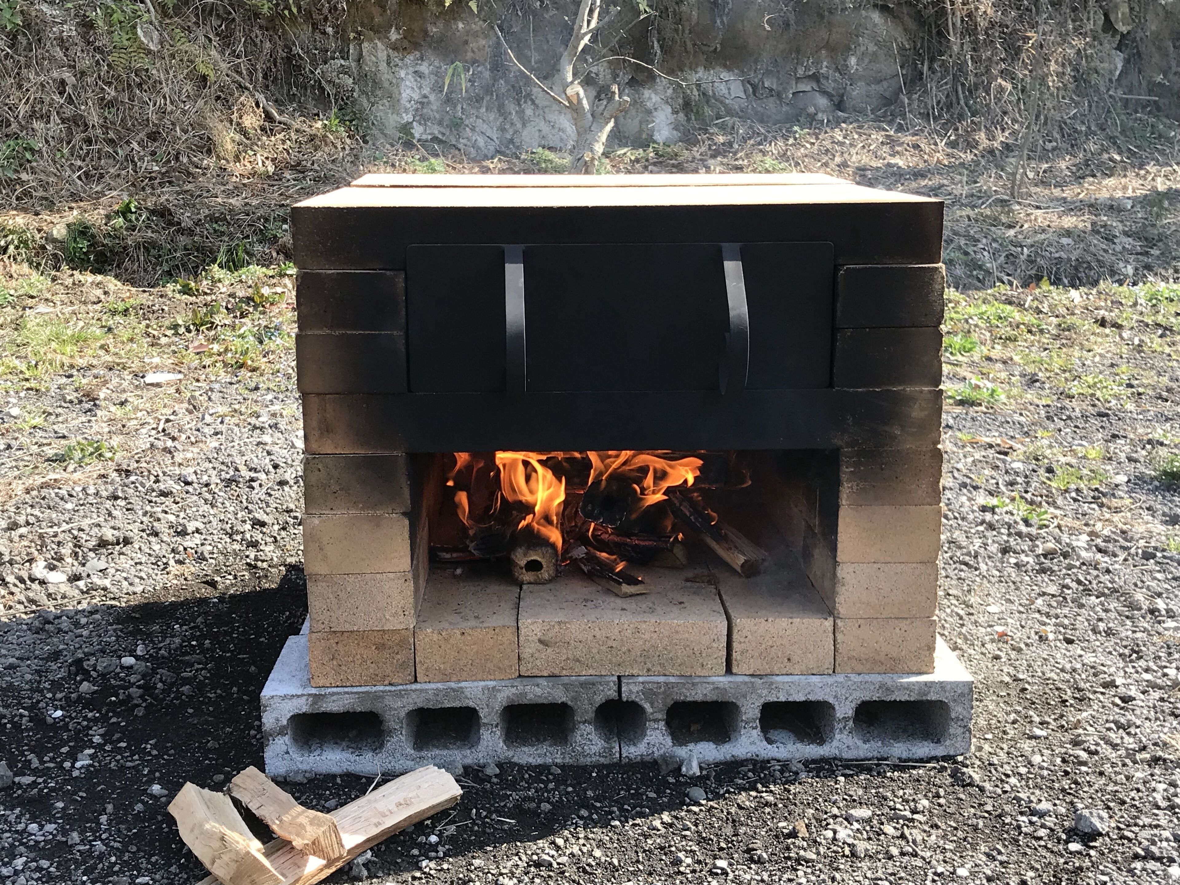 A portable brick fireplace with a fire burning inside.