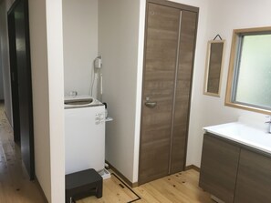 A compact bathroom with a wooden wardrobe, a white sink, and a mirror above it. - Sasayakana Ouchi S Nogi (Futtsu)