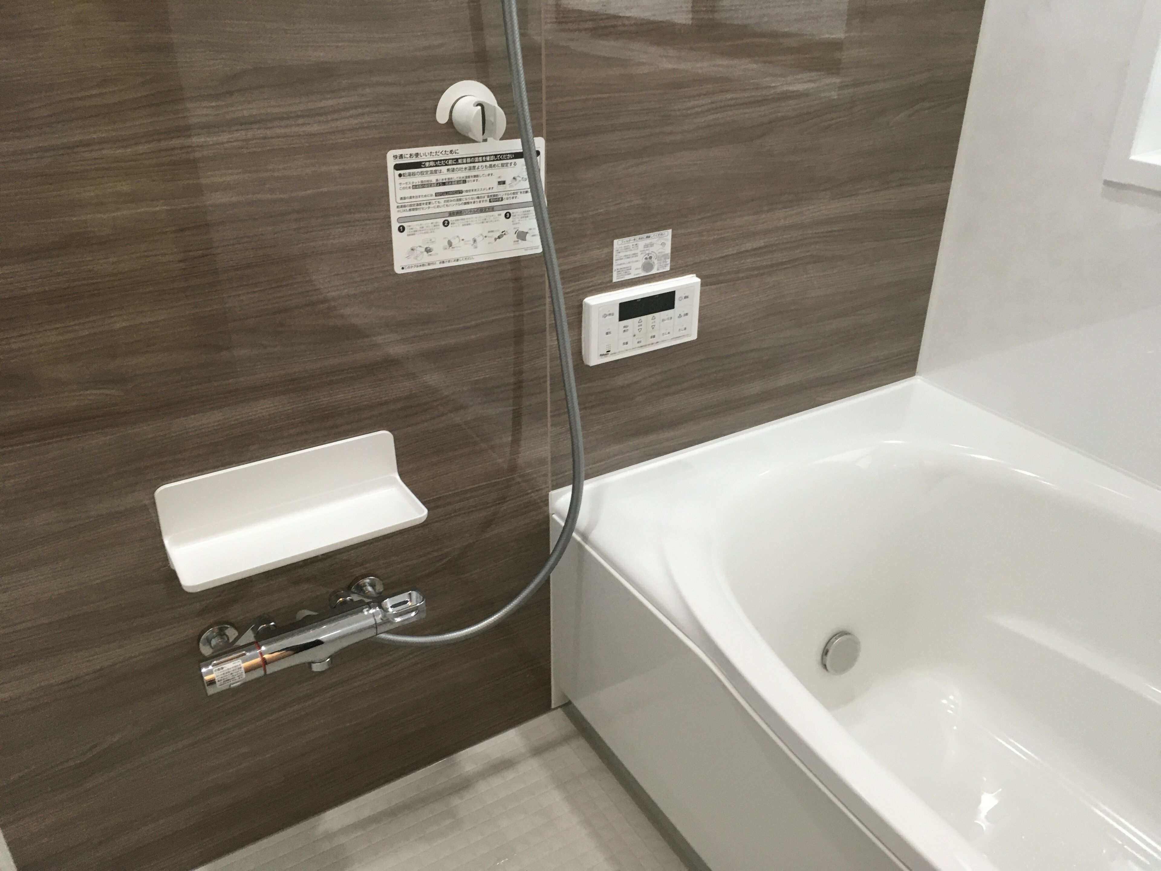 Une salle de bain moderne équipée d’une baignoire, d’un panneau de commande pour la douche et d’un porte-serviettes.