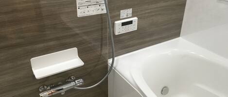 Une salle de bain moderne équipée d’une baignoire, d’un panneau de commande pour la douche et d’un porte-serviettes.