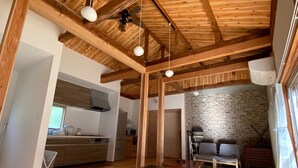 A spacious kitchen with wooden beams, a brick wall, and a dining area with benches. - Sasayakana Ouchi S Nogi (Futtsu)