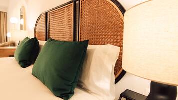 A neatly made bed with green and white pillows, a woven headboard, and a bedside lamp.