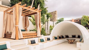 Un espace de détente extérieur moderne, doté d’une pergola en bois, de sièges rembourrés et d’une table basse en verre.
