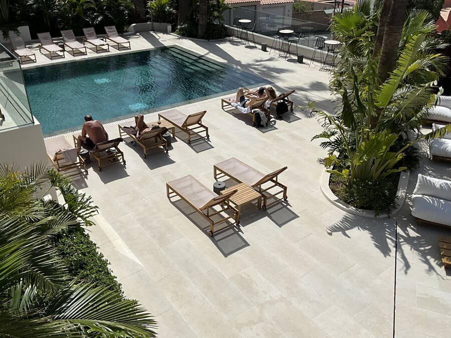 Un área junto a la piscina con sillones de descanso, una mesa y una pequeña alberca.