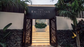 L’entrée de l’hôtel Estefania Boutique Suites se distingue par un mur en pierre, un jardinier orné de plantes et un sol carrelé à motifs.